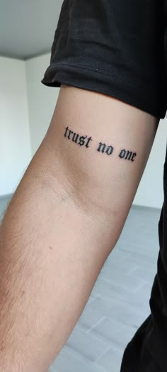 a man's arm with the words trust no one tattooed on it