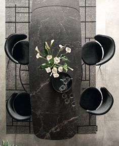 an overhead view of a dining table with chairs and a vase on the center piece