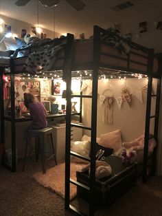 a woman sitting on top of a bunk bed next to a desk