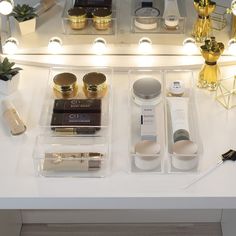 an assortment of beauty products displayed in front of a lighted mirror on a white counter