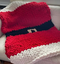 a red and white crocheted blanket sitting on top of a couch next to a pillow