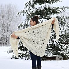 a woman is walking in the snow with a shawl over her shoulders and boots on