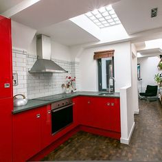 a kitchen with red cabinets and stainless steel appliances