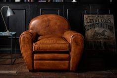 a brown leather chair sitting in front of a book shelf