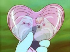 a person holding a cell phone in front of a heart shaped object with two cats on it