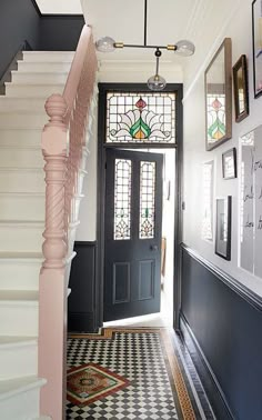 a hallway with black and white checkered flooring, framed pictures on the wall