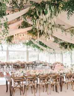 an elegant tented wedding reception with white and pink flowers, greenery and chandeliers