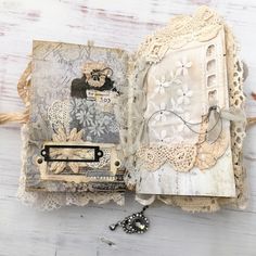 an open book with lace and buttons on it sitting on top of a wooden table