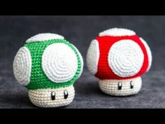 two crocheted nintendo mushroom toys sitting next to each other on a gray surface