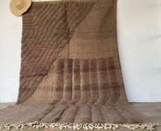 a brown and white rug with fringes on the floor in front of a wall