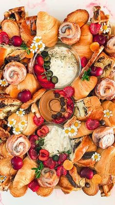 a platter filled with croissants, strawberries and other food items