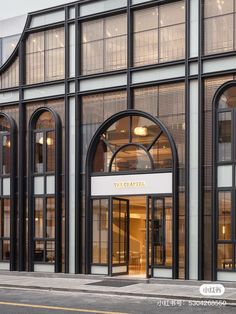 the entrance to a large building with arched glass doors and windows on both sides is shown