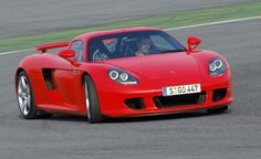 a red sports car driving on a race track with the driver in the front seat