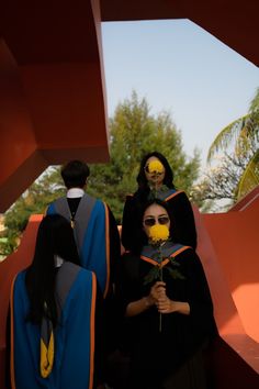 three women dressed in black and yellow standing next to each other with flowers on their heads