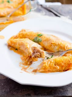 an omelet is being eaten on a white plate with a fork and knife