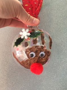 a hand is holding a christmas ornament with a reindeer face on it and snowflakes hanging from the top