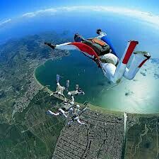 a man flying through the air on top of a red white and blue parachute over a city