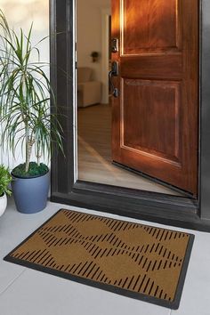 a brown door mat sitting on top of a floor next to a potted plant