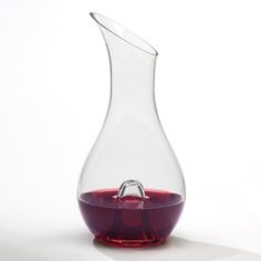 a wine decanter with a red liquid in it on a white table top