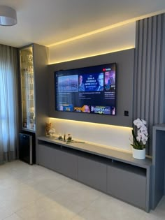 a large flat screen tv mounted on the wall in a living room next to a window