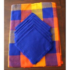 six blue and orange napkins sitting on top of a wooden table next to each other