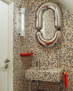 a bathroom with a sink, mirror and toilet paper roll on the wall next to it