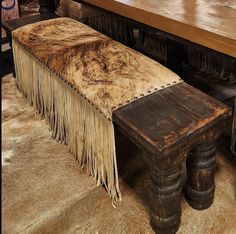 an old bench with fringes on it sitting in front of a wooden table