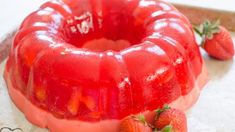 a red jelly bunt cake with strawberries on the side and another strawberry in the background