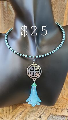 a necklace with a blue tassel and a green bead is on top of a mannequin