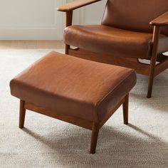 a brown leather chair and ottoman in a room