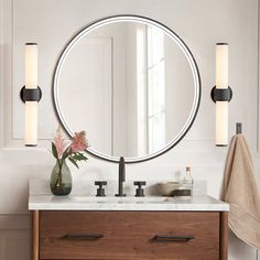 a bathroom vanity with a round mirror above it and two lights on either side of the sink