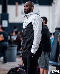 a man standing in front of a crowd wearing a white shirt and black sweatpants