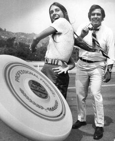 two people standing next to each other near a frisbee