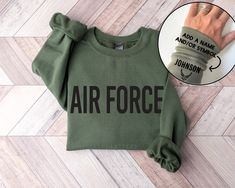 Pictured above in the sweatshirt color Military Green with Black colored design print. See all shirt details in the listing photos. FIND THE T-SHIRT VERSION HERE: https://www.etsy.com/listing/1365809282/air-force-shirt-with-name-personalized?click_key=72a2a5f948f583d5ef656947c6d9d5f05ab1bbff%3A1365809282&click_sum=0dbfa674&ref=shop_home_active_1&sts=1 Please read the FAQ's & POLICIES section before ordering. Police Force Gifts, Us Air Force Merchandise, Air Force Gifts Teepublic, Christmas Gifts For Airforce Boyfriend, Air Force Gifts Motherproud, Air Force Retirement Shirt, Gf Things, Air Force Decor, Air Force Uniform