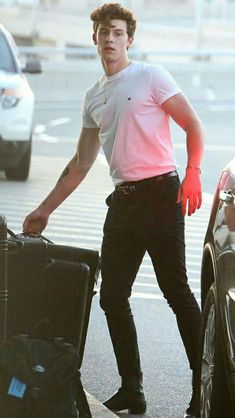 a young man is carrying his luggage down the street