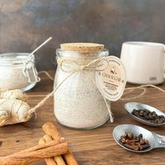 some cinnamon sticks and spices are on a wooden table next to a glass jar filled with white stuff