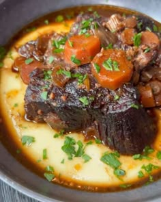 a close up of a plate of food with meat and vegetables in sauce on it