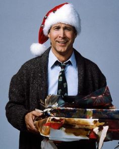 a man in a suit and tie is wearing a santa claus hat while holding presents