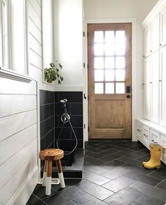 a black and white tiled bathroom with a wooden door, stools, and potted plant