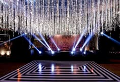 a stage with lights and chandeliers hanging from it's ceiling is lit up