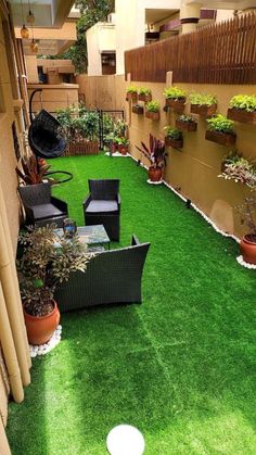 an outdoor patio with artificial grass and potted plants on the side of the building