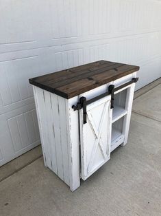 an old white cabinet with sliding doors on the front and sides is sitting outside in front of a garage door