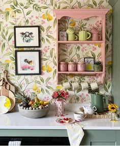 a kitchen counter with plates and cups on it next to a wallpapered wall