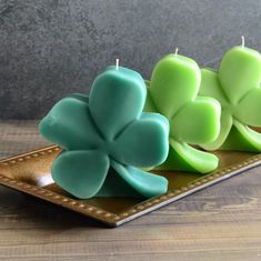 three candles are sitting on a plate with four clover shaped candles in the shape of shamrocks