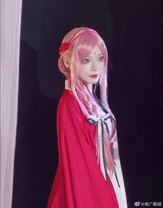 a mannequin with pink hair wearing a red cape