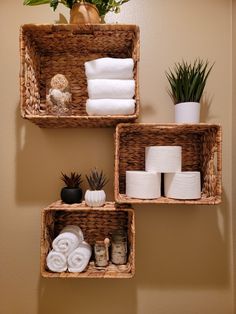 three baskets with towels and other items on them in the corner of a bathroom wall