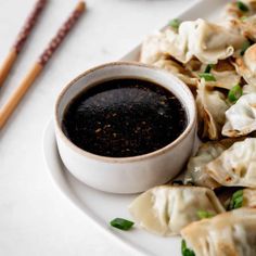 a white plate topped with dumplings covered in sauce