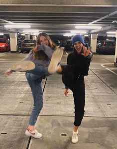 two young women are playing with frisbees in a parking garage while smiling