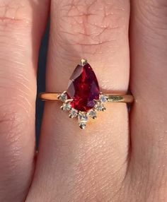 a woman's hand with a ring on it and a red stone in the middle