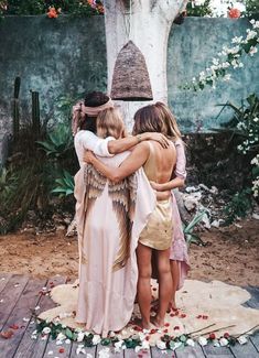 two women hug each other while standing in front of a tree with flowers on it